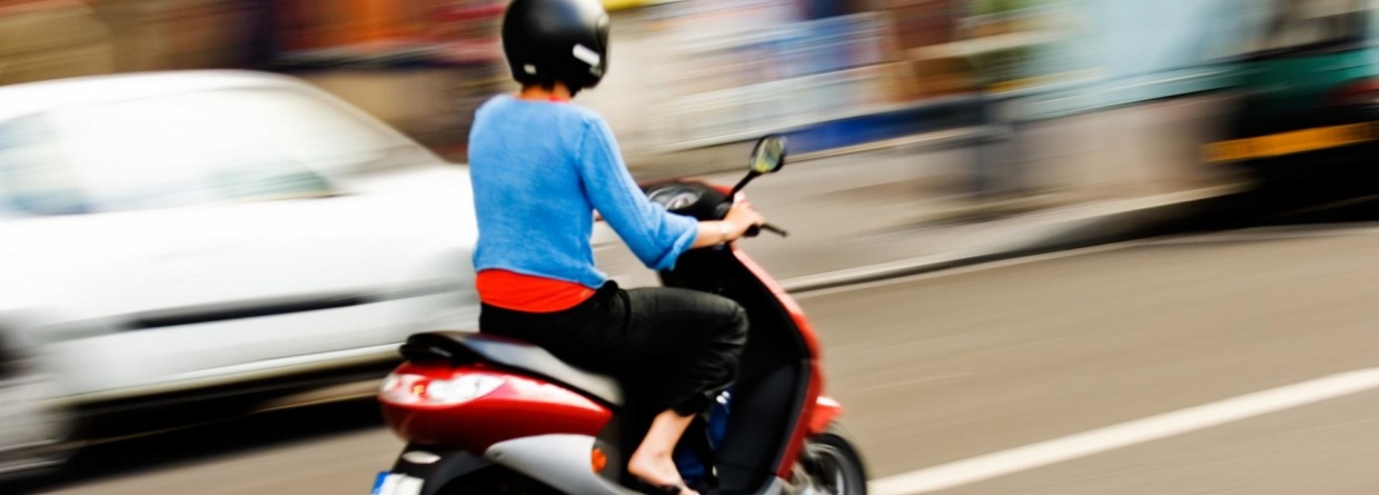 Vrouw met scooter rijdt snel over de weg