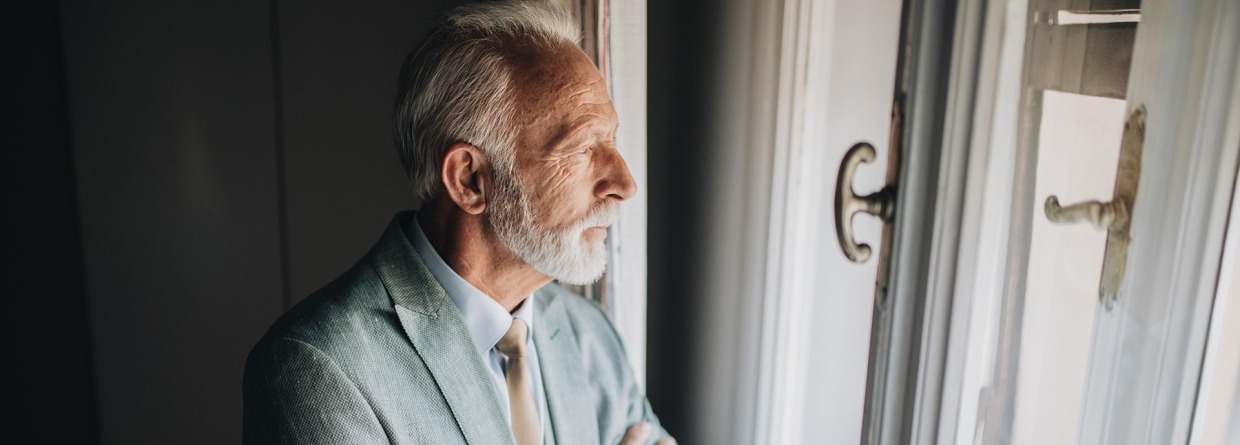 Bezorgd zakenman op zoek door het raam van een appartement