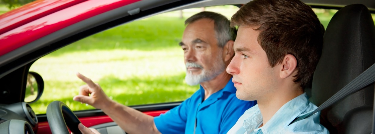 Jonge jongen achte het stuur in de auto met een oudere man ernaast 